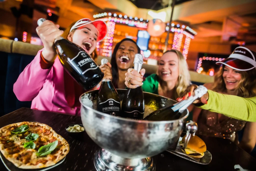 Women grabbing prosecco from an ice bucket at Puttshack